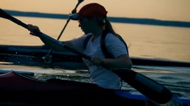 Zijaanzicht van een vrouwelijke watersporter tijdens het peddelen — Stockvideo