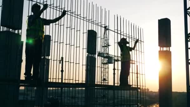 As pessoas trabalham com postes de metal em um canteiro de obras . — Vídeo de Stock