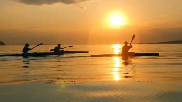 Wasserlandschaft bei Sonnenuntergang mit Paddlern, die daran entlang segeln — Stockvideo