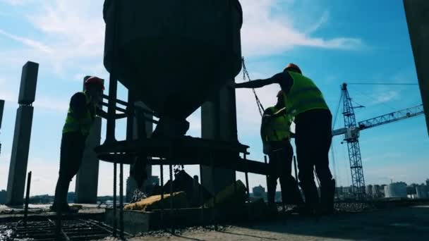 Les travailleurs de la construction versent du ciment à partir d'un conteneur sur un site . — Video