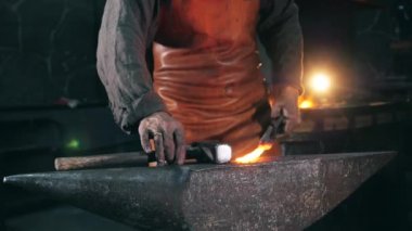 Demirci metal dövmek için çekiç kullanıyor.