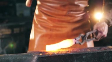 Isıtmalı metal alet ustası tarafından dövülüyor.