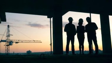 İşçiler inşaat alanında durup konuşuyorlar. Modern şantiyede inşaat işçileri.