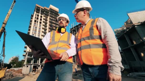 Engenheiros trabalham em um local de construção. Trabalhadores da construção civil no canteiro de obras moderno . — Vídeo de Stock