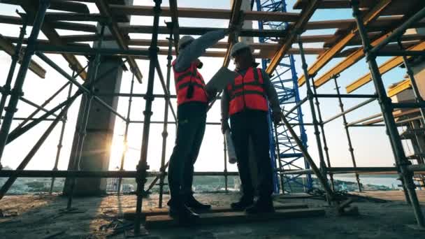 Trabajadores en pie uniforme en edificio inacabado . — Vídeos de Stock