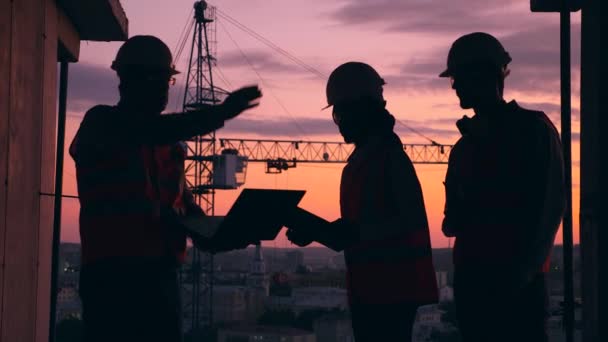 Men and a woman work on a building site, checking blueprint. — Stock Video