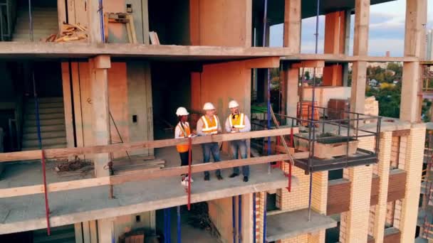 Hombres y una mujer trabajan en una obra, hablando . — Vídeos de Stock