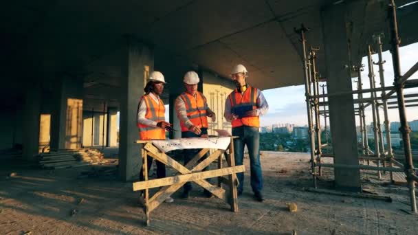 Μηχανικοί κατασκευών εργάζονται σε μια ιστοσελίδα, συζητώντας για δουλειά. — Αρχείο Βίντεο