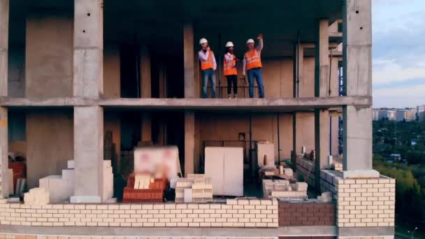 工作的工程师站在一座大楼里讨论建筑问题. — 图库视频影像