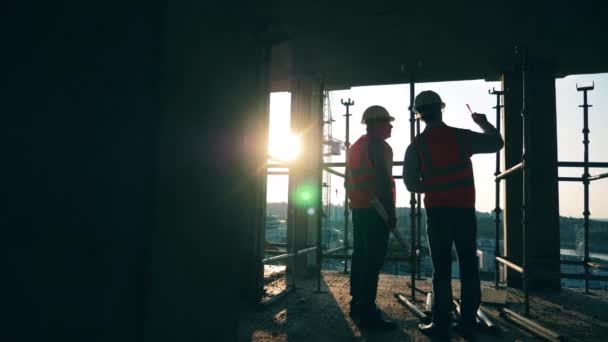 Byggnadsarbetare kontrollerar en byggnad. — Stockvideo