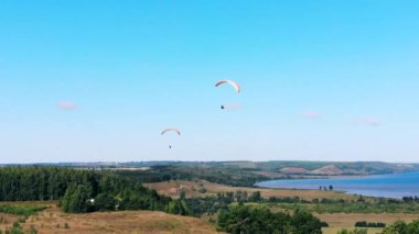 İnsanlar yerden havadan paraşütle uçuyor.