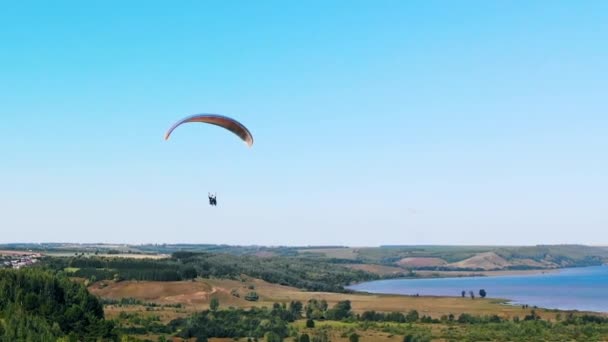 Tandemflug mit dem Gleitschirm über den Feldern — Stockvideo