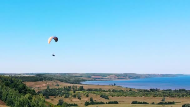 People are flying over the land and water on the paraplane. Man Paragliding. beautiful nature background. — Stock Video