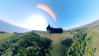 Tarlaların üzerinde bir şahıs koç-hava paraşütüyle uçuyor. İnsan paragliding, güzel doğa arka planı.