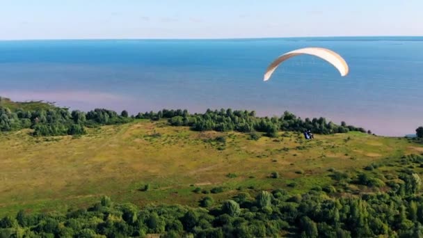 Een koppel vliegt boven het water op de parawing — Stockvideo