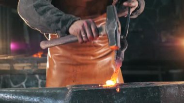 Demir ağır çekimde bir demirci tarafından dövülmektedir.