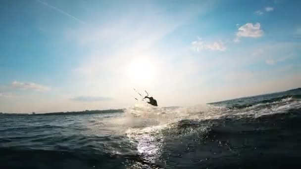 Een kitesurfer spettert water terwijl hij op een plank zit. Vlieger surfer kiteboarden. — Stockvideo