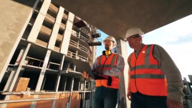 Dizüstü bilgisayarı olan iki mimar bina boyunca yürüyorlar.