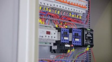 Elektrikçi elektriği test ediyor. Sanayi fabrikası elektrikçisi elektrik kalkanında çoklu metre kullanarak voltajı test ediyor..