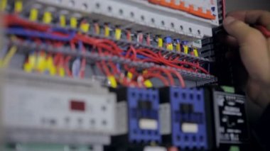 Elektrikçi elektriği test ediyor. Sanayi fabrikası elektrikçisi elektrik kalkanında çoklu metre kullanarak voltajı test ediyor..