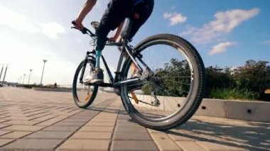 Biyonik bacaklı bir adam dışarıda bisiklet sürüyor.