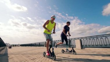 Bacak destekli adamlar dışarıda scooter kullanıyor.