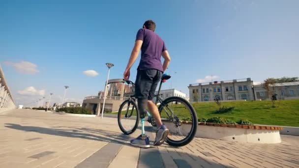 Мужчина с заменой ног идет с велосипедом — стоковое видео