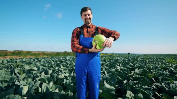 Agriscientista, agrario profesional, agricultor sonríe mientras sostiene una col — Vídeo de stock