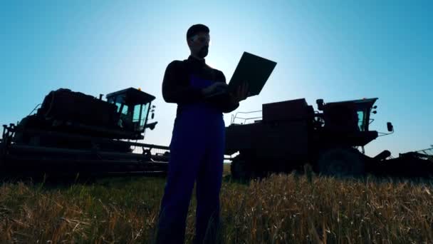 Mezőgazdasági gépek és egy férfi agronómus áll a közelben — Stock videók