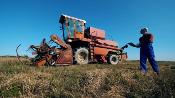 Combine vehicle and an agriscientist walking around it — Stock Video