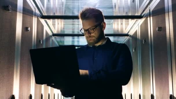 Het specialist types op laptop tijdens het werken in de serverruimte. — Stockvideo