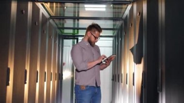 Bir mühendis sunucu odasındaki bilgisayarları kontrol eder.