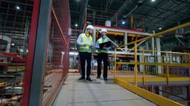 İşçiler tesisteki fabrika makinesini kontrol ediyorlar..