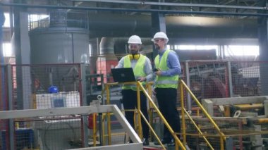 İki mühendis bir tuğla fabrikasında çalışan makineleri kontrol ediyor..