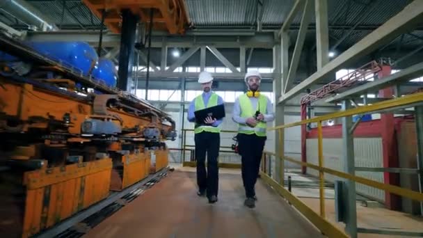 Gli ingegneri camminano in una struttura di fabbrica, controllando le macchine della fabbrica di mattoni . — Video Stock