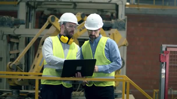 Ingenieros en uniforme trabajan con un portátil en una instalación . — Vídeo de stock