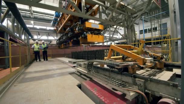 Ingenieros masculinos revisan una máquina mientras trabaja con ladrillos . — Vídeos de Stock