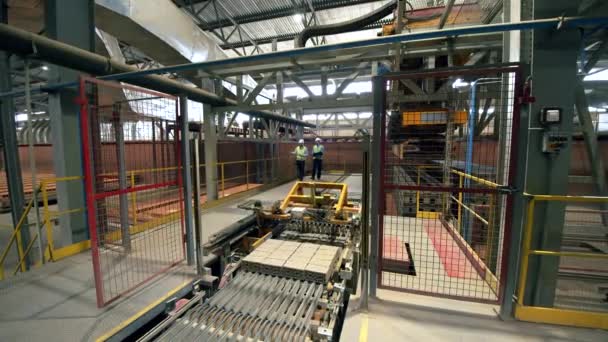 Ingenieros revisan máquinas que trabajan con ladrillos en una planta . — Vídeos de Stock