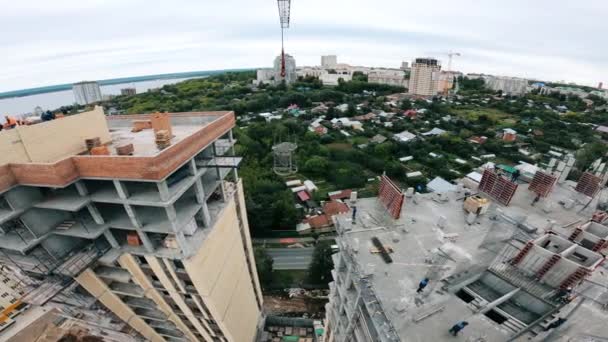 Vista superior de los edificios en construcción con los trabajadores en ellos — Vídeos de Stock