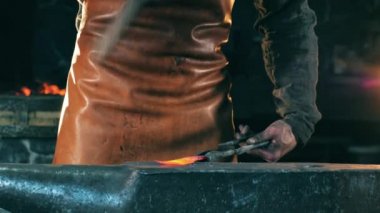 Demirhane işçisi çekiçle bıçağa vurur..