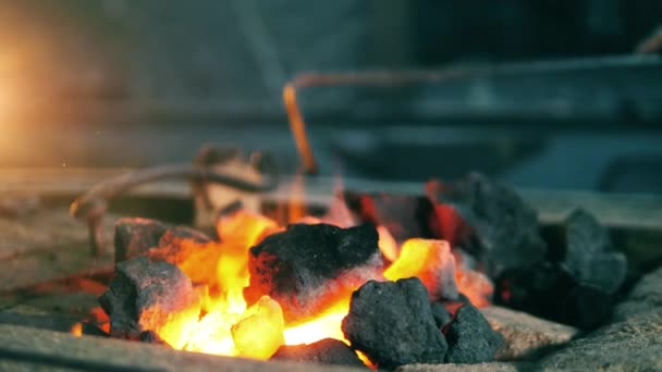 Kovář pohybuje uhlím v plamenech. — Stock video