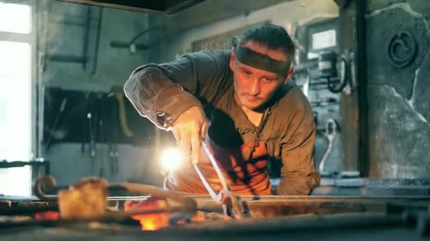 One blacksmith holds hot knife with tongs. — Stock Video