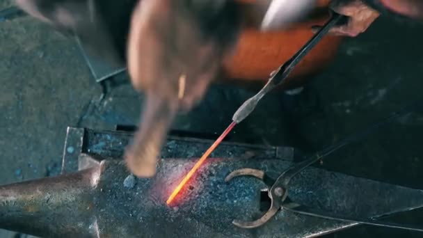 Un hombre golpea un cuchillo en el yunque, usando un martillo de metal . — Vídeo de stock