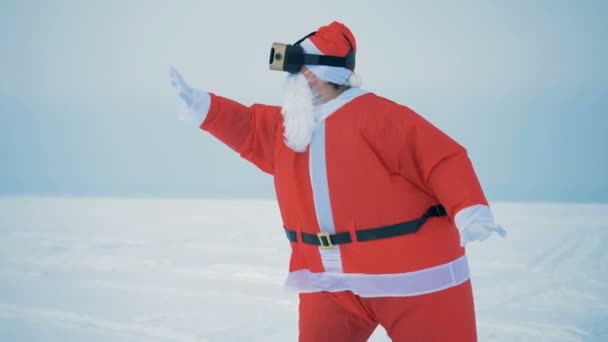Snowy landscape with Santa Claus in VR-glasses grabbing air — Stock Video