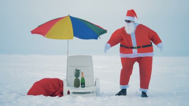 Strand-Oase inmitten eines verschneiten Feldes mit tanzenden Weihnachtsmännern — Stockvideo