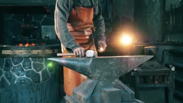 Un homme travaille avec un couteau sur une enclume à une forge . — Video