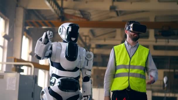 Un hombre con gafas VR trabaja con un droide blanco . — Vídeo de stock