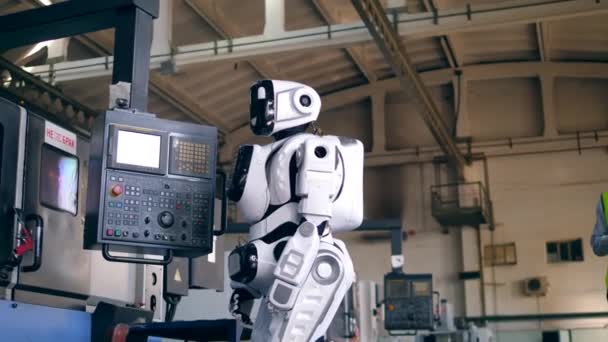 Plant worker controls a droid, using a tablet in a facilty. — Stock Video