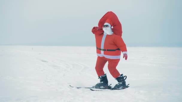Santa Claus en esquís está tratando de caminar contra el viento — Vídeo de stock