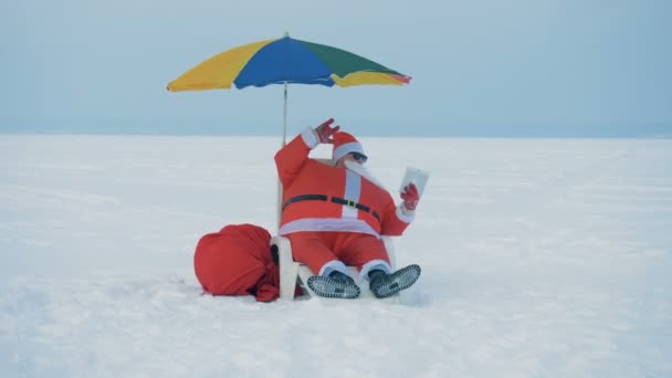 Videocall de Santa Claus sentado en una tumbona en la nieve — Vídeo de stock